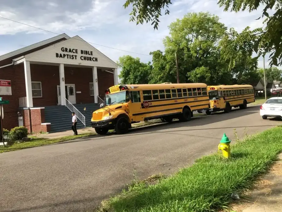 A yellow church bus parked in front of the brick Grace Bible Baptist Church building