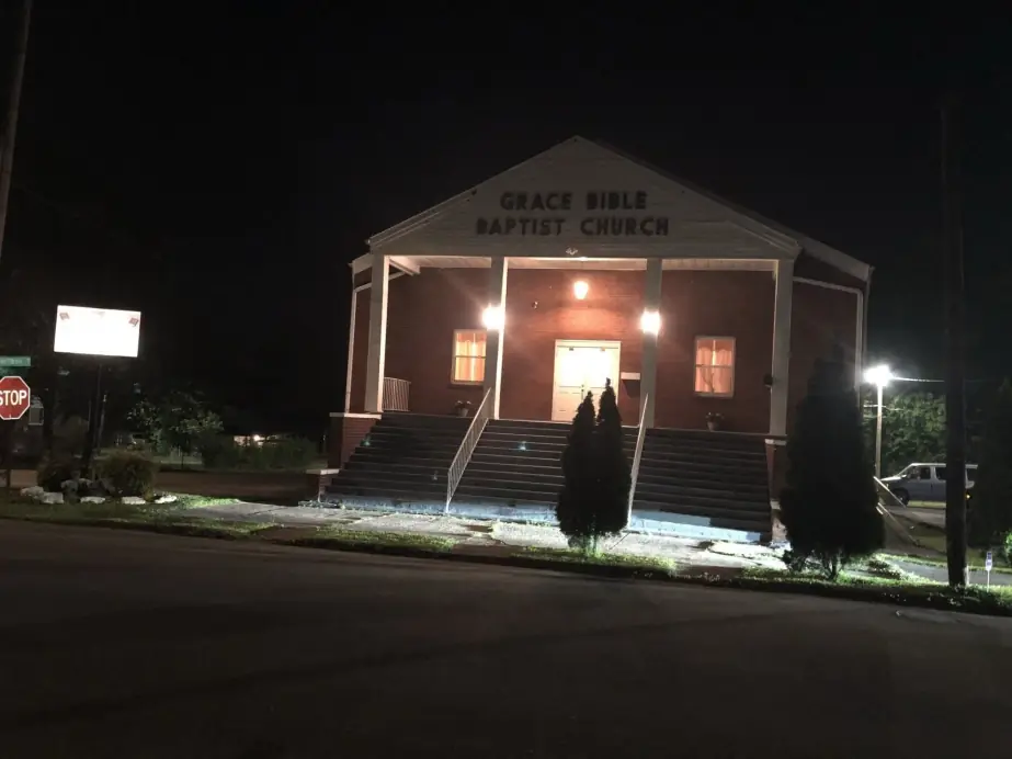 The lit front steps and sign of Grace Bible Baptist Church on Jefferson Avenue at night