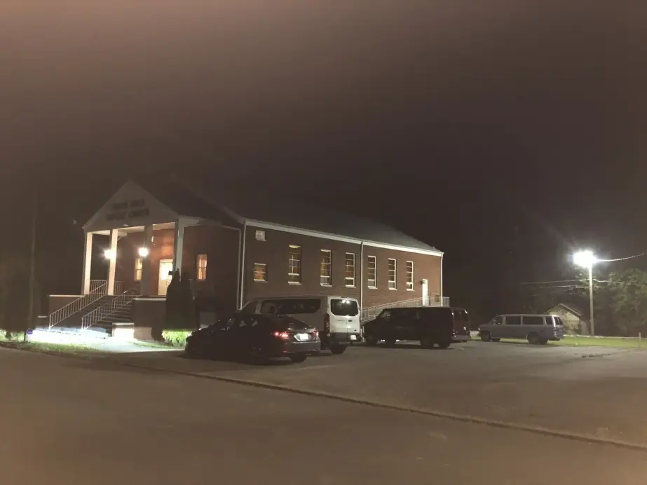 The church from the street at night with cars parked out front