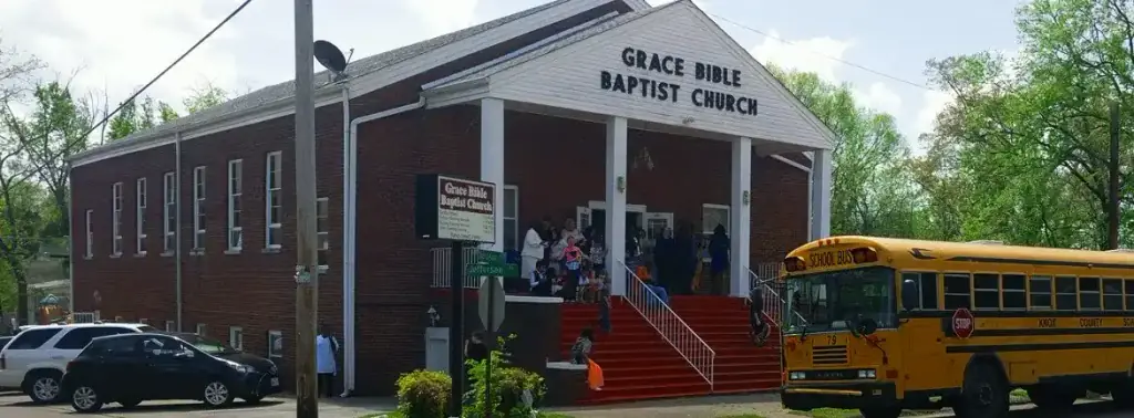 The front of the church by day with two church buses parked along the street