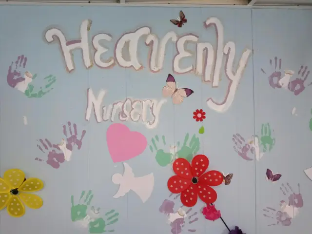 A painted wall with children's handprints and the words Heavenly Nursery