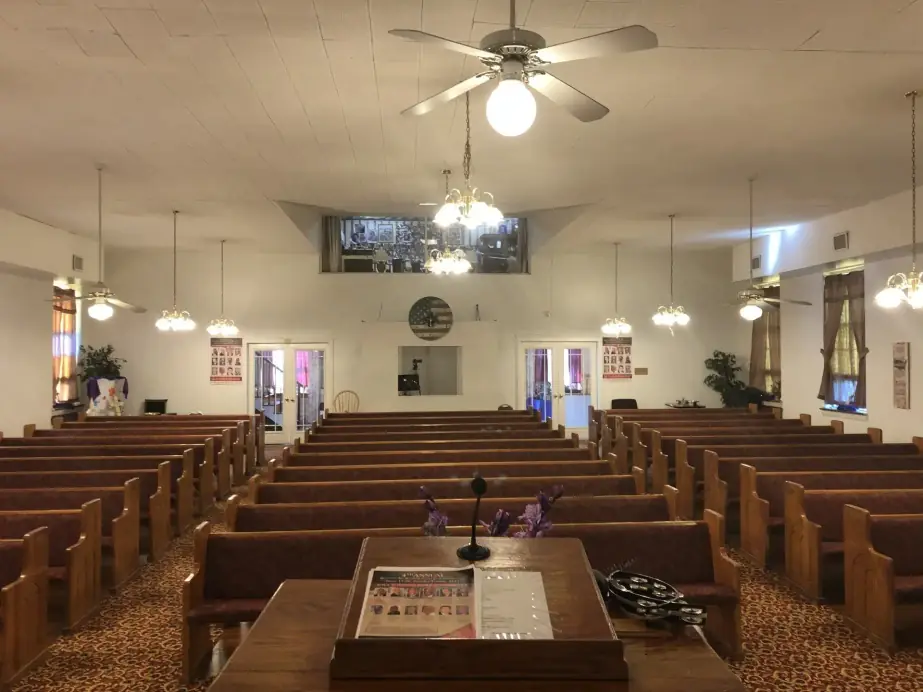 Pews leading toward the platform beneath a ceiling fan