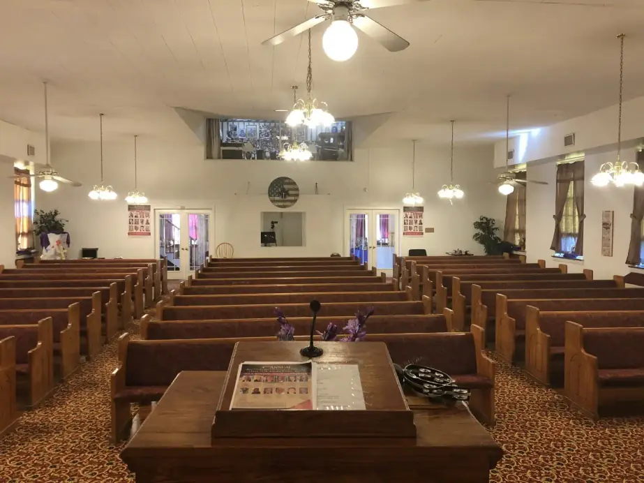 Rows of oak pews under pendant lamps in the Grace Bible Baptist Church sanctuary