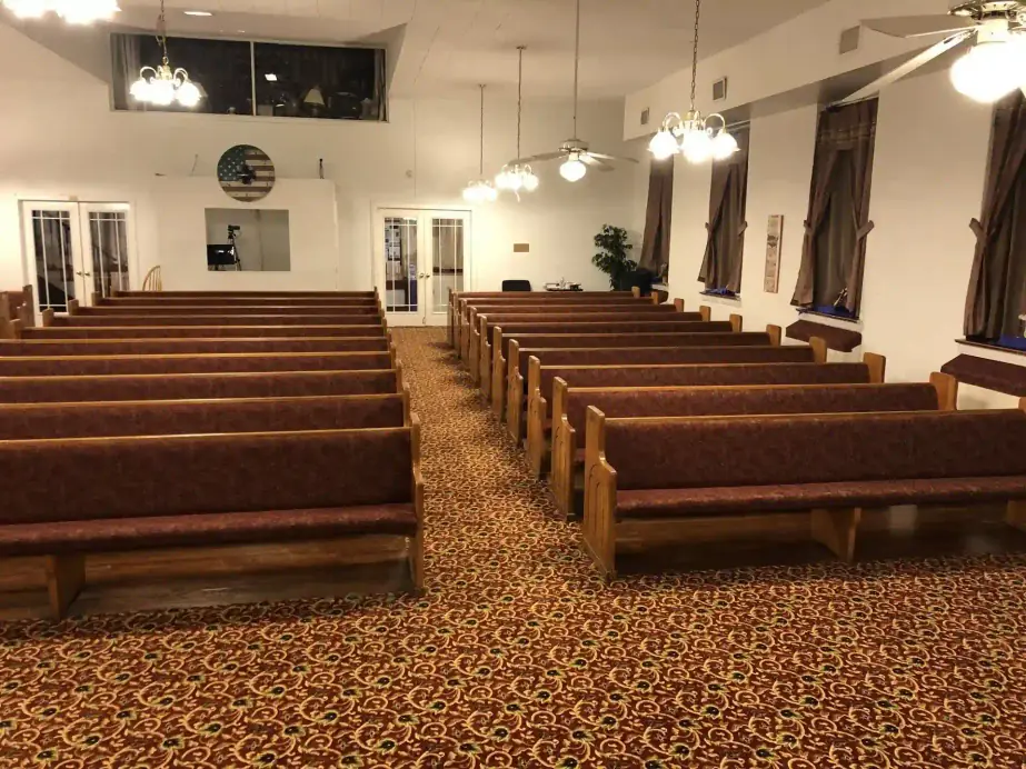 Rows of oak pews with burgundy cushions in the Grace Bible sanctuary